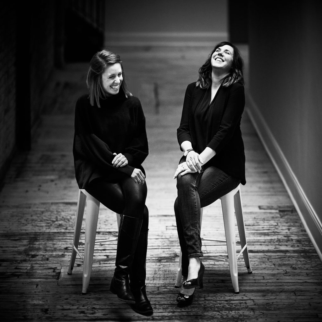 Faith and Stacy sitting on stools together and laughing