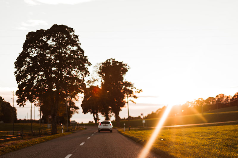 A car driving into the sunset